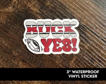May include: A 3-inch waterproof vinyl sticker with the words "Buckeyes!" in red and white stripes. The sticker also features a football.