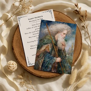 Könnte beinhalten: Zwei Karten auf einem Holztablett. Eine Karte zeigt den Text "SAINT PATRICK Blessing for the Path" und ein Gedicht. Die andere Karte ist eine Aquarellillustration von St. Patrick mit einem Kleeblatt und Stab, mit langem weißem Bart.