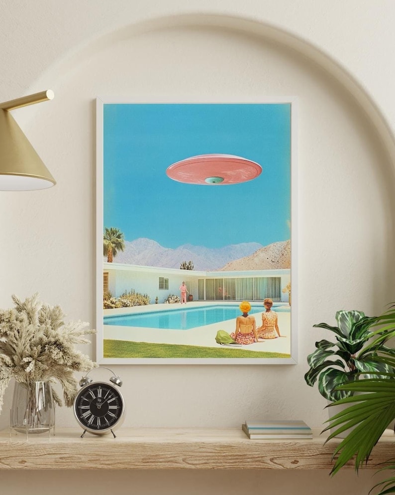 May include: A retro-style illustration of a pink flying saucer hovering over a swimming pool in a desert landscape. Two people are sitting by the pool, looking up at the saucer.
