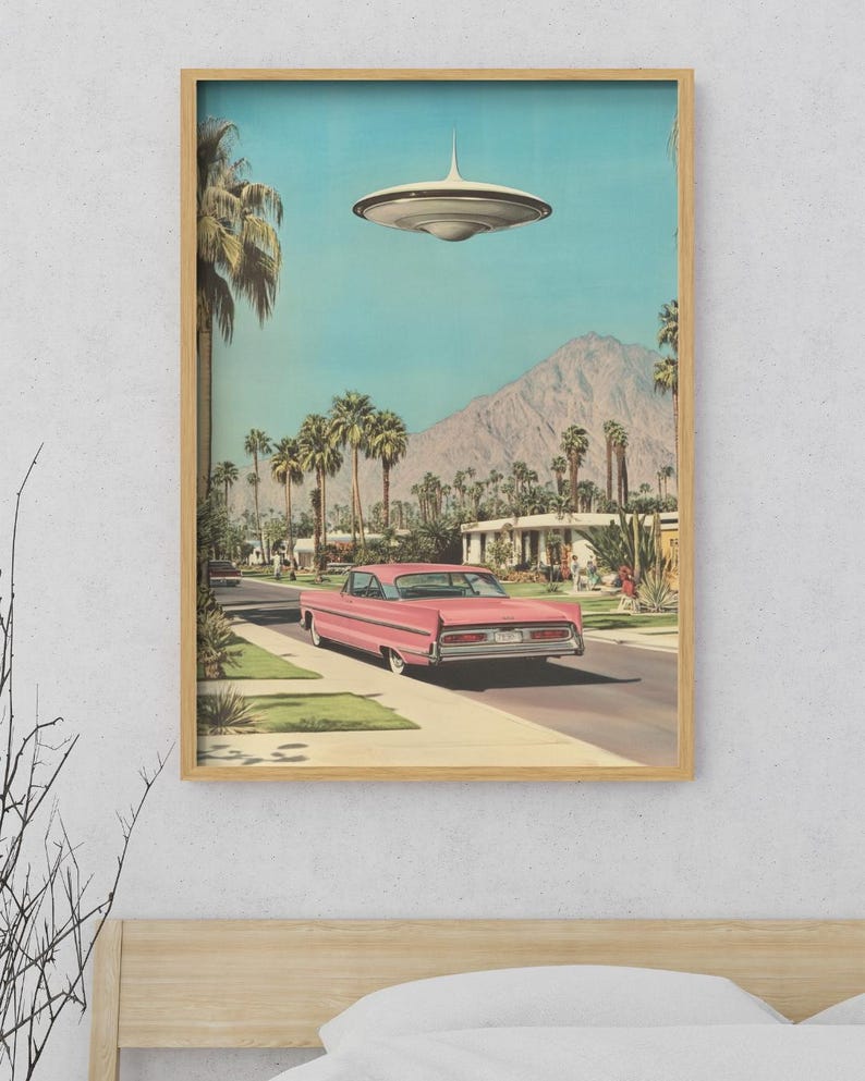 May include: A pink vintage car drives down a suburban street with palm trees and a mountain in the background. A flying saucer hovers above the street.