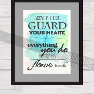 May include: A framed watercolor print with a teal, blue, and green background. The print features the text "ABOVE ALL ELSE, GUARD YOUR HEART, for everything you do flows from it." and the scripture reference "PROVERBS 4:23".