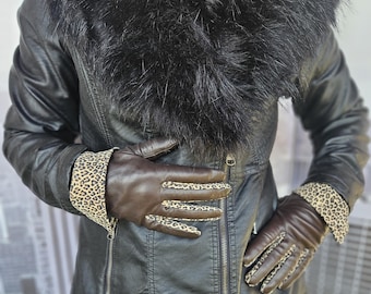 Puede incluir: Una chaqueta de cuero negra con cuello de piel sintética y guantes de cuero marrón con forro de estampado de leopardo.