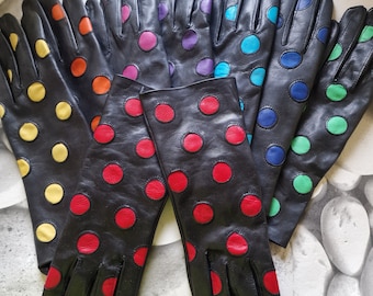 Op de afbeelding: Een set van tien lange zwarte leren handschoenen met kleurrijke stippen. De handschoenen hebben een polsband. De stippen zijn in verschillende kleuren, waaronder geel, oranje, rood, paars, blauw en groen.