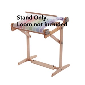 May include: A wooden loom stand with a rainbow colored loom on top. The stand is made of natural wood and has a simple design. The text "Stand Only. Loom not included" is visible in the image.