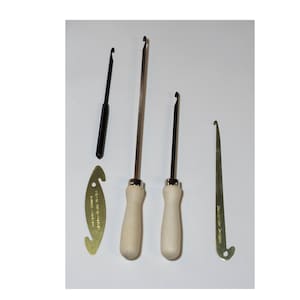 May include: Set of four tools for leather craft. Two tools have wooden handles and metal hooks. One tool has a black handle and a metal hook. One tool is a metal hook with a brass handle.