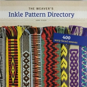 May include: A book titled "The Weaver's Inkle Pattern Directory" by Anne Dixon, featuring a colorful display of 400 warp-faced weaves.