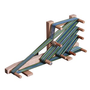 May include: A wooden loom with green and blue striped yarn threaded through it. The loom has a wooden frame and multiple pegs for holding the yarn.