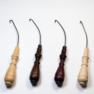 May include: Four wooden crochet hooks with metal hooks. The hooks are in natural wood, dark brown, reddish brown, and light brown.
