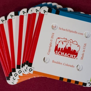 Puede incluir: Un abanico de tarjetas Schacht Spindle, con fondo blanco y bordes rojos y naranjas. Las tarjetas muestran el logotipo de Schacht, el sitio web y el texto "Made in USA". Las tarjetas est&aacute;n etiquetadas con las letras A, B, C y D.
