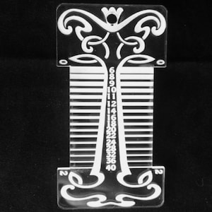 May include: White plastic ruler with a decorative design at the top and bottom. The ruler has markings from 6 to 40.