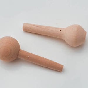 May include: Two wooden knobs with a round and a bulbous shape. The knobs are made of light brown wood and have a small hole in the center.