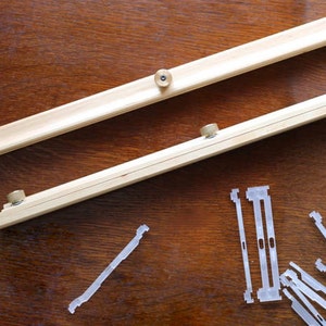 May include: Two wooden stretcher bars with brass knobs and a pile of white plastic canvas stretcher bar clips.