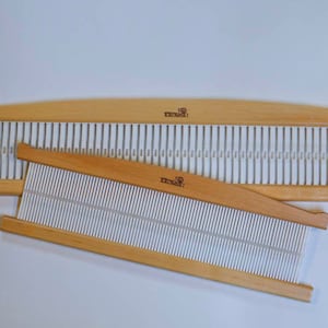May include: Two wooden weaving looms with white stringing. The larger loom is curved and the smaller loom is straight. Both looms have the word "remarkable" printed on them.
