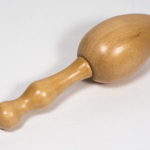 May include: A wooden egg-shaped yarn winder with a long, curved handle. The handle has a rounded knob at the end.