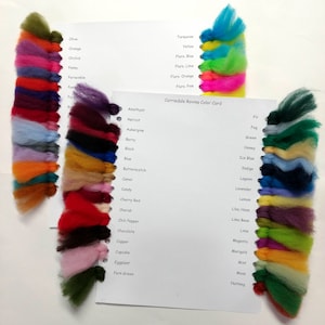 May include: A color card with wool samples in various colors, including turquoise, yellow, lime, orange, pink, amethyst, apricot, aubergine, berry, black, blue, butterscotch, camel, candy, cherry red, cherub, chili pepper, chocolate, copper, cupcake, eggplant, fern green, fir, fog, green, honey, ice blue, indigo, lagoon, lavender, lemon, lilac haze, lima bean, lime, magenta, marigold, mint, moss, and nutmeg. The card is titled "Corriedale Roving Color Card".
