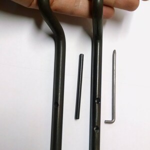 May include: Two black metal rods with a curved end and two holes. A small black metal rod and a silver metal rod with a bent end are also included.