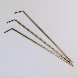 May include: Three silver metal drinking straws with a slight bend at the top.