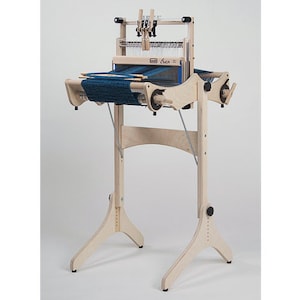 以下が含まれることがあります： 青い経糸と3本の脚が付いたスタンドが付いた木製の織機。織機には「Crick」というラベルが貼られており、織物に人気があります。