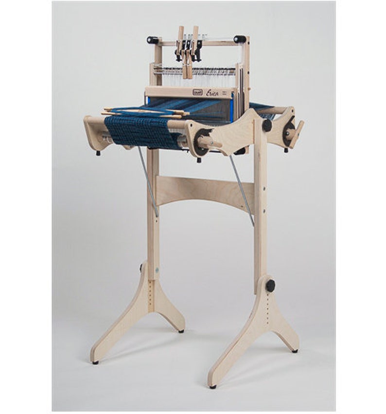 以下が含まれることがあります： 青い経糸と3本の脚が付いたスタンドが付いた木製の織機。織機には「Crick」というラベルが貼られており、織物に人気があります。