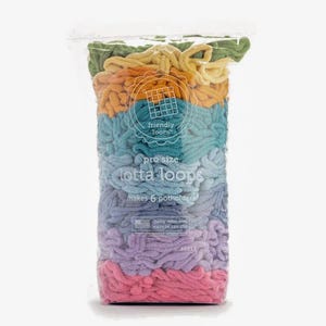 May include: A clear plastic bag filled with colorful, looped yarn. The yarn is arranged in horizontal bands of green, yellow, orange, teal, light blue, lavender, and pink. Text on the bag reads "friendly loom" and "pro size lotta loops makes 6 potholders."