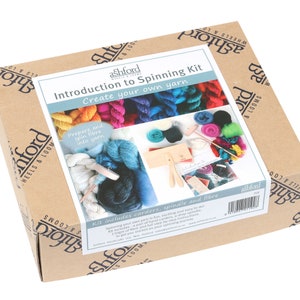 May include: A cardboard box with the text "Introduction to Spinning Kit" and "Create your own yarn". The box contains a spinning kit with carders, a spindle, and fiber. The kit is from Ashford Wheels & Looms.