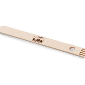 May include: A wooden weaving tool with a handle and a row of teeth at one end. The tool is branded with the text "SCHACHT".