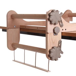 May include: A wooden loom with a beige tension knob labeled "Pro-Tension" and a beige warp beam with a beige tension knob labeled "Pro-Tension".