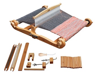 May include: A wooden loom with a gray and orange woven fabric on it. The loom is set up with a shuttle and a heddle. The loom is surrounded by various wooden tools and supplies, including a wooden dowel rod, a wooden shuttle, a wooden heddle, and a wooden comb.