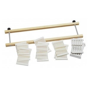 May include: A wooden loom with white plastic weaving heddles. The loom is made of natural wood and has a simple design. The heddles are used to create different patterns in woven fabric.