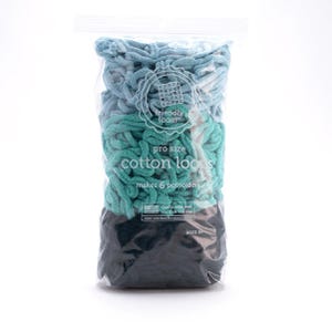May include: A clear plastic bag filled with pro size cotton loops in shades of blue, teal, and black. The bag has a white label with the text "friendly loom" and "makes 6 potholders". The product is for ages 8+.