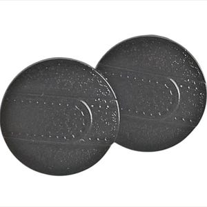 May include: Two dark gray, circular objects with a textured surface. Each object has a curved indentation and a series of small, evenly spaced dots. The objects are slightly overlapping, set against a white background.
