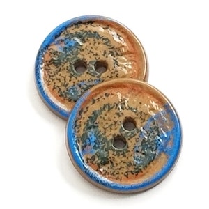 May include: Two ceramic buttons with a brown, orange, and blue glaze. The buttons have two holes each.