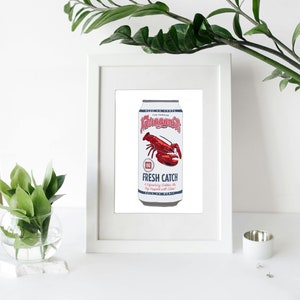 May include: A framed print featuring a can of Narragansett Fresh Catch beer. The can is white with red and blue text and a red lobster graphic. The print is displayed on a white surface with greenery.