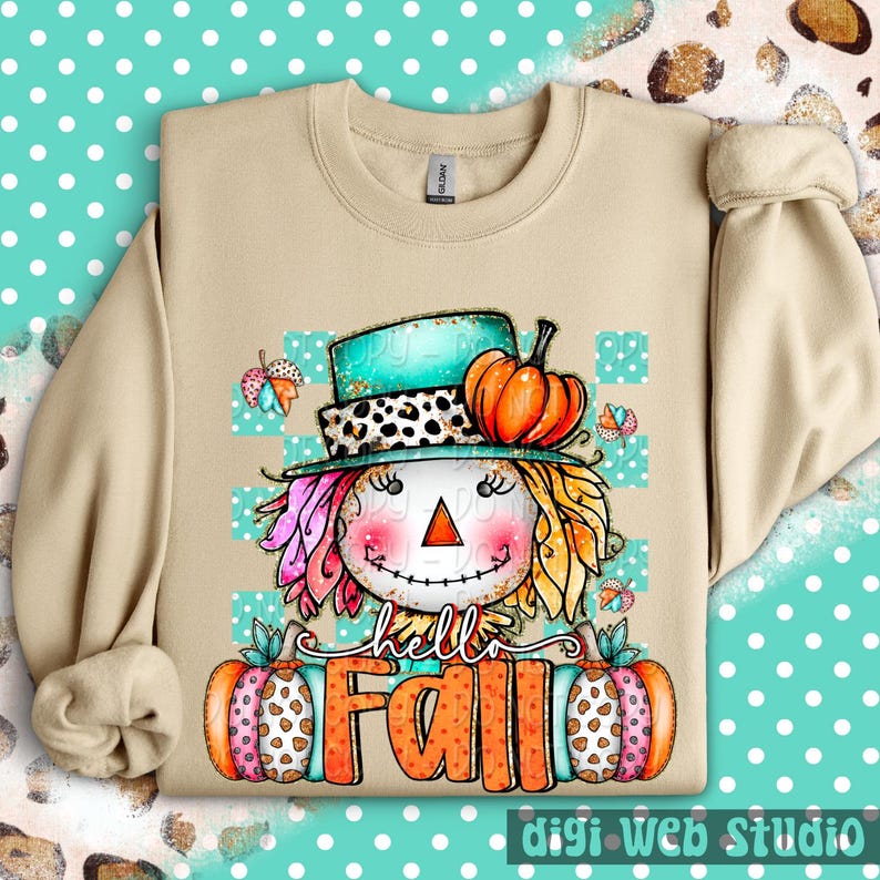 May include: Beige sweatshirt featuring a whimsical scarecrow design with a turquoise hat, orange pumpkin, and the text "hello Fall." The scarecrow has colorful hair and a smiling face. The design includes butterflies and pumpkins.