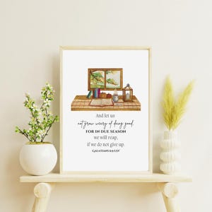 May include: A framed print with the text "And let us not grow weary of doing good." The artwork features a watercolor illustration of a window, books, and a lantern. A white vase with flowers and a decorative vase with tall grass are on a wooden shelf.