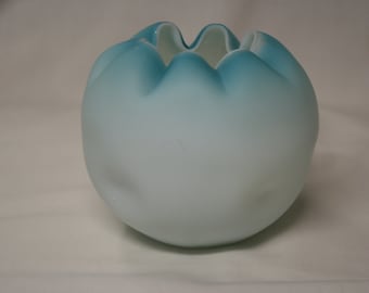 May include: A white and light blue glass bud vase with a ruffled top.
