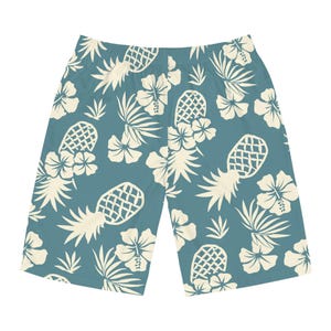 Könnte beinhalten: Eine Shorts in gedämpftem Blaugrün mit einem durchgehenden Muster aus cremefarbenen Ananas, Hibiskusblüten und tropischen Palmblättern. Die Shorts verfügen über einen standardmäßigen elastischen Bund und eine locker geschnittene Beinform.