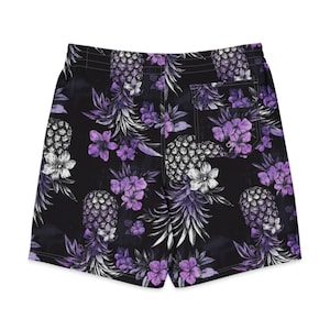 Può includere: Costume da bagno nero con un motivo ripetuto di ananas viola e fiori tropicali viola. Il pantaloncino include un elastico in vita e una singola tasca posteriore con chiusura a patta, caratterizzato da una stampa floreale e fruttata uniforme.