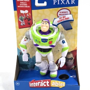 Könnte beinhalten: Eine Buzz Lightyear Actionfigur in Originalverpackung. Das Spielzeug trägt einen weißen, grünen und violetten Raumanzug. Die Verpackung enthält den Text Pixar, Interactables, Buzz Lightyear, To Infinity and Beyond und Try Me.