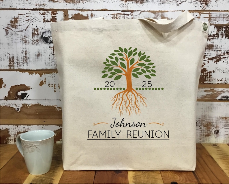 May include: A white canvas tote bag with a green tree design and the text "Johnson FAMILY REUNION". The tree has orange roots and a line of green dots with the numbers 20 and 25.