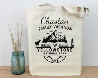 Könnte beinhalten: Cremefarbene Tragetasche mit schwarzem Text und Grafiken. Der Text lautet "Chastan Family Vacation" über einer Berglandschaft mit einem Elch, einem Adler und einer Felsformation. Darunter steht "Yellowstone National Park 2025".