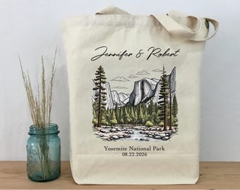 Könnte beinhalten: Eine weiße Canvas-Tragetasche mit schwarzem Text, der "Jennifer & Robert" lautet, und einer Schwarzweißillustration des Yosemite-Nationalparks. Der Text unter der Illustration lautet "Yosemite National Park 08.22.2026".