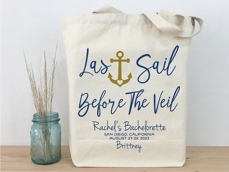 May include: A white canvas tote bag with a navy blue and gold design that says "Last Sail Before The Veil". The bag also includes the text "Rachel's Bachelorette", "San Diego, California", "August 27-29, 2023", and "Brittney".