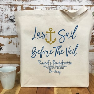 May include: A white canvas tote bag with a blue and gold design. The text on the bag reads "Last Sail Before The Veil" with an anchor symbol. The text below reads "Rachel's Bachelorette, San Diego, California, August 27-29, 2023, Brittney".