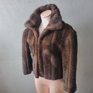 May include: A brown faux fur jacket with a zipper closure and a high collar.