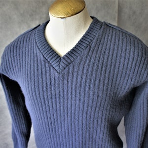 May include: A blue ribbed knit sweater with a v-neck and long sleeves.