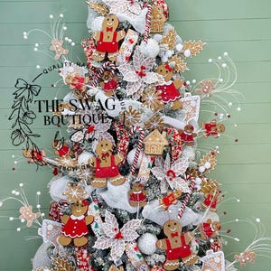 May include: A decorated Christmas tree with gingerbread man ornaments, red and white accents, and the text "THE SWAG BOUTIQUE". The tree features white ribbon, holly leaves, and candy cane decorations, creating a festive holiday display.
