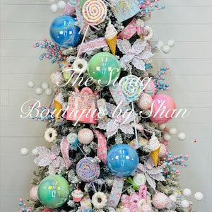 May include: A decorated Christmas tree with a whimsical candy theme. It features colorful ornaments, lollipops, ice cream cones, and gift box decorations. The tree is adorned with pink and blue ribbons and sits in a woven basket.