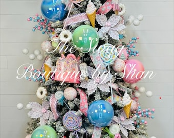 Puede incluir: Un árbol de Navidad decorado con un tema de dulces. Cuenta con adornos coloridos, piruletas, conos de helado y decoraciones de cajas de regalo. El árbol está adornado con cintas rosas y azules y se encuentra en una cesta tejida.