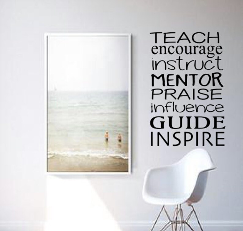 May include: A white framed picture of a beach scene with two people in the water. The wall behind the picture has a black vinyl decal with the words "TEACH, ENCOURAGE, INSTRUCT, MENTOR, PRAISE, INFLUENCE, GUIDE, INSPIRE".